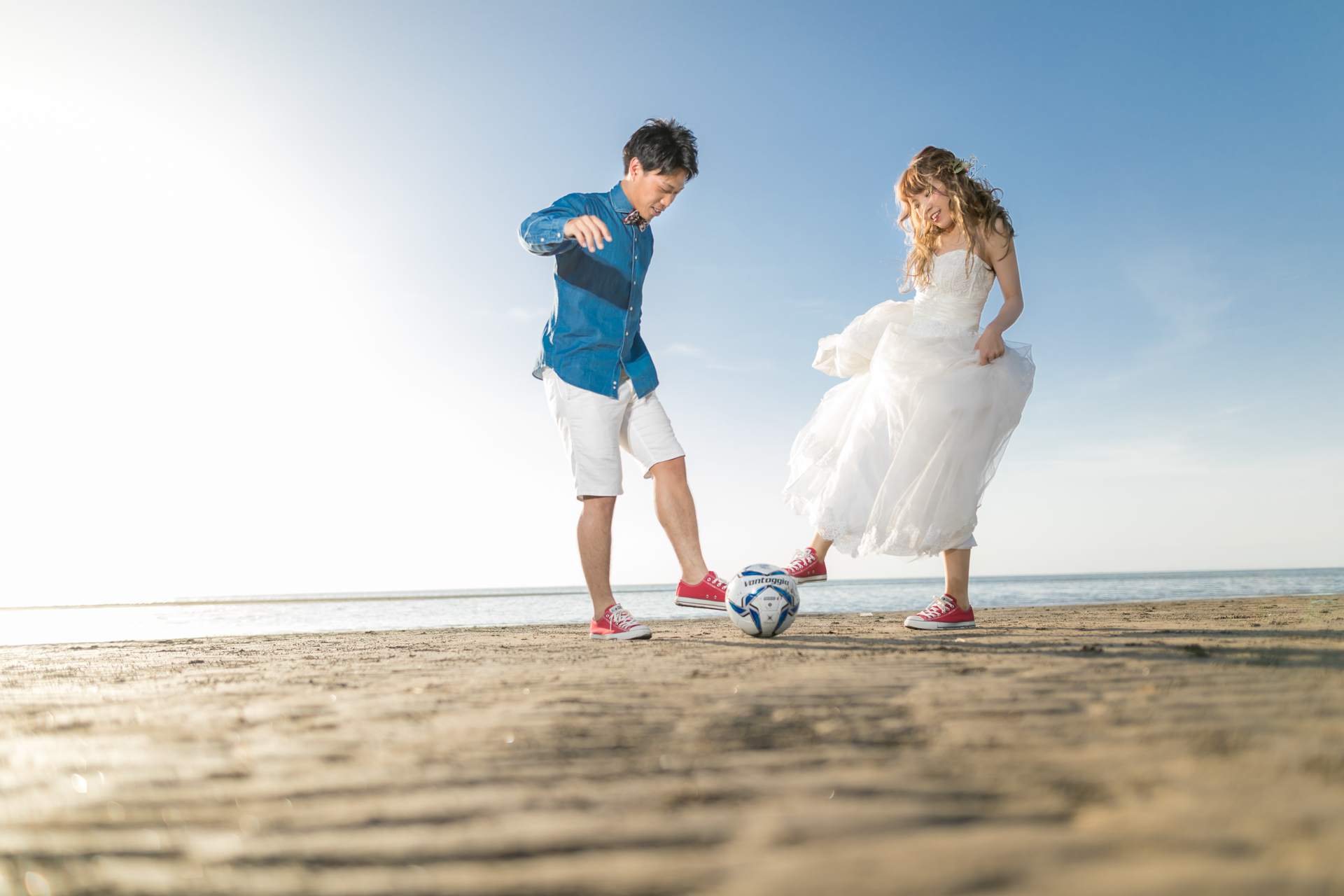 大分の砂浜でお気に入りのおもちゃ（サッカーボール）を使ってのびのび遊ぶ赤ちゃんとパパママ