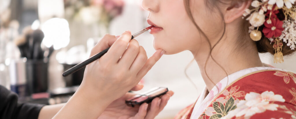 大分の婚礼前撮りで、色打掛姿の花嫁がヘアメイクスタッフにリップメイクをしてもらうお支度風景