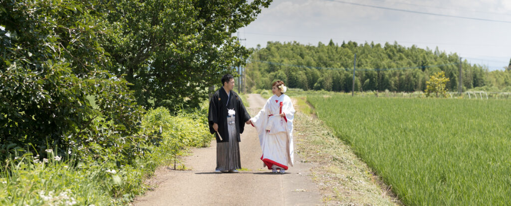 緑豊かな田園風景を手をつないで歩く和装の新郎新婦|大分のフォトウェディング・Photostudio PASSION