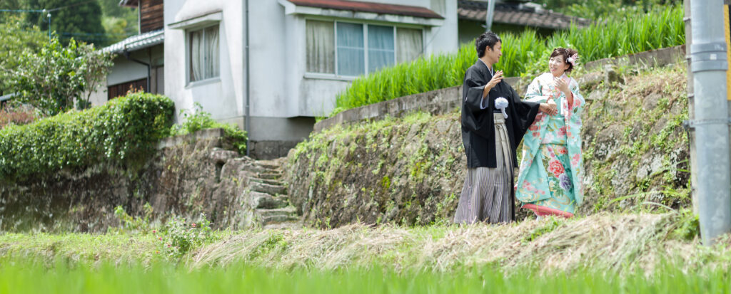 大分のおばあちゃんの家で和装フォトウェディング。思い出のある田園風景の中を、色打掛と紋付袴姿のお二人が楽しそうに歩く自然な姿を撮影。